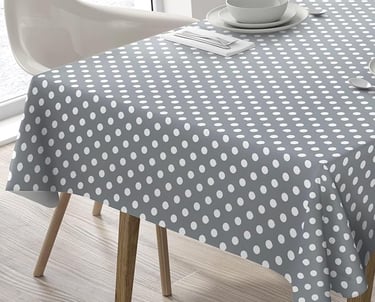 Modern grey and white polka dot tablecloth draped over a dining table with place settings.