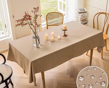 Elegant tan waterproof tablecloth on a rectangular dining table with candles and flowers.