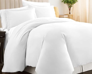 a bed with a white bedding and a plant