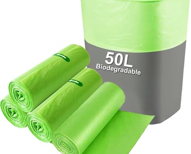 a green trash canister with a roll of garbage bags