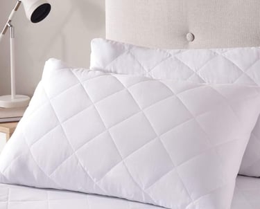 a bed with a white pillow and pillows