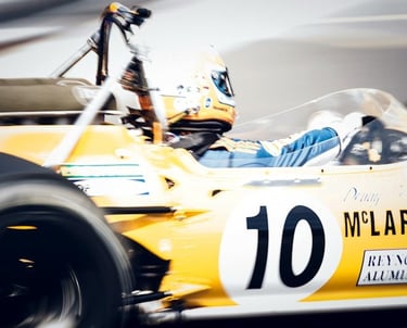 Vintage yellow McLaren Formula 1 race car with number 10 speeding on Monaco track with motion blur.
