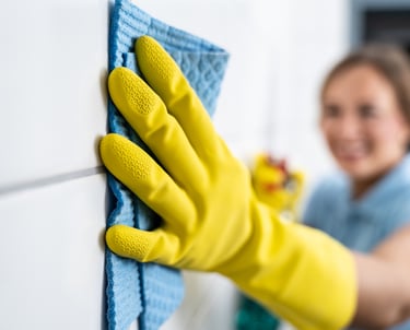 a woman in yellow gloves cleaning a wall