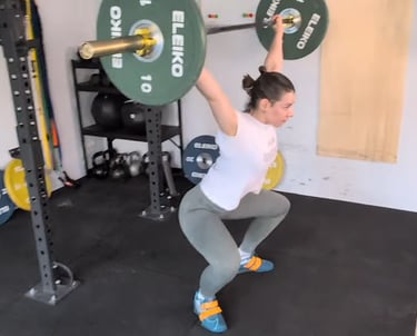 Eine Frau führt ein Reißen (Snatch) mit einer Langhantel aus.