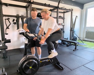 Frau auf Concept2 BikeErg mit Personal Trainer in Bielefeld.