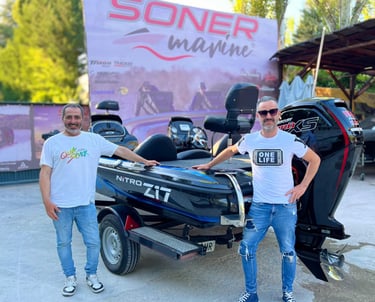 two men standing next to a boat with a motorbike