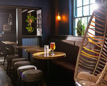 An egg chair next to some small round tables with drinks on 1 table