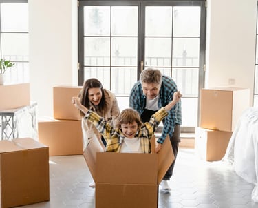 a family moving into a new house, boxes with a child in a cardboard box