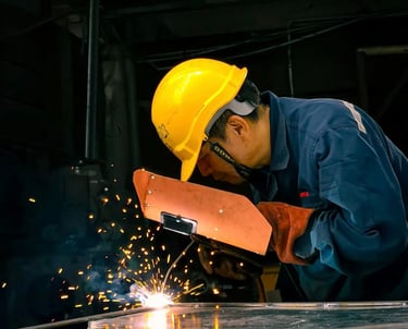 a man in a yellow helmet welding a piece of metal