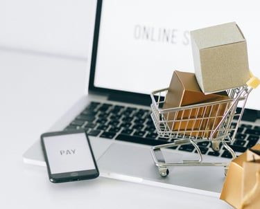 Laptop with a miniature trolley of boxes representing online shopping