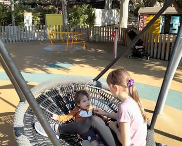 two young girls sitting on a swing - frame