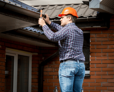 Ein Mann was eine Dachrinne repariert