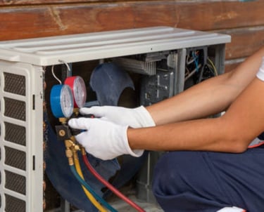 a man in a white shirt and gloves is fixing a heat pump
