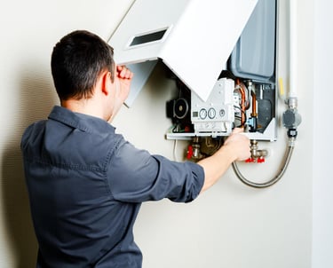 a man in a blue shirt is fixing a tankless water heater