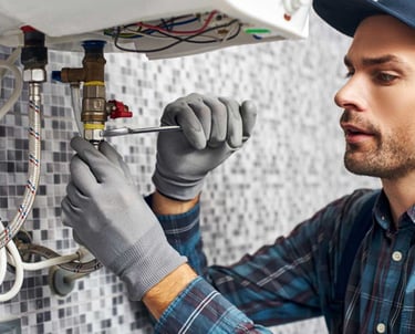 a man in a hat and gloves is fixing a water heater