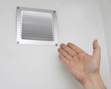 a hand holding a small metal venting venting in a bathroom