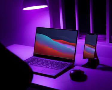 a laptop computer sitting on a desk with a purple light