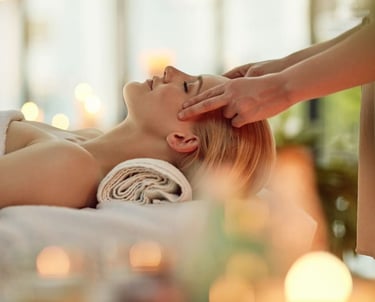 Mujer disfrutando de un masaje relajante en la cabeza en un entorno de spa, rodeada de velas y ambiente cálido, representando