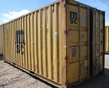 A yellow cargo worthy high cube shipping container with rust dents and dings