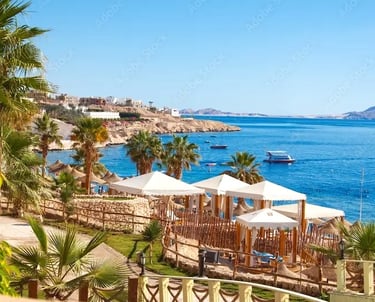 Praia de areia branca em Hurghada com resorts de luxo em frente ao Mar Vermelho turquesa. Ao fundo, a Marina de Hurghada