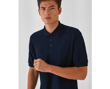 a man in a blue shirt and jeans standing in front of a white wall