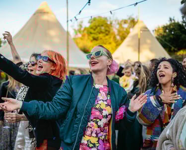 Wedding guests dancing and singing at Ceridwen Centre outdoor wedding in South Wales, captured by photographer Owen Mathias
