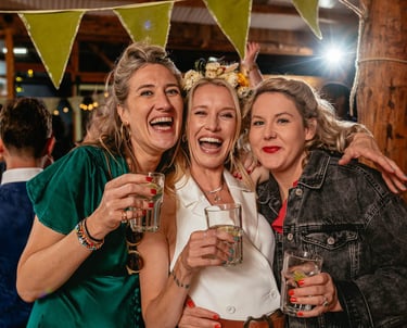 Bride and friends laughing with drinks during South Wales wedding reception, captured in candid style by photographer Owen Ma