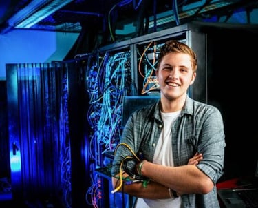 a man in a server room with a laptop and a laptop