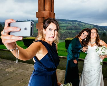 Bridesmaid taking funny selfie with bride and guest at South Wales wedding, captured candidly by photographer Owen Mathias