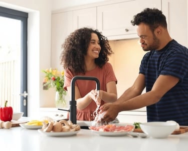 Care worker assisting a person to wash hands at a kitchen sink, supporting daily living tasks