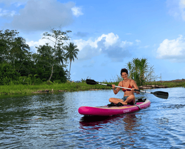 A girl smiles at the camera during a standup paddle board tour with camping babsita caribbean coast