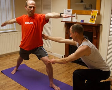 a man being corrected in a yoga pose by a yoga teacher