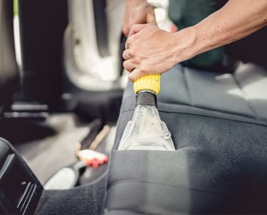a person cleaning a car seat in a vehicle