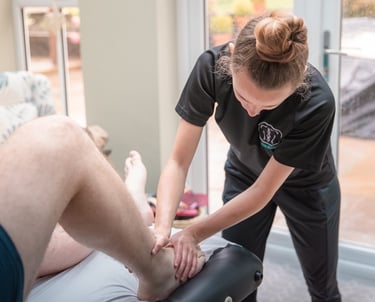 Sports Therapist conducting an ankle injury assessment on a client