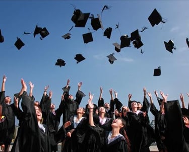 a group of graduates in black caps and gowns throwing their caps