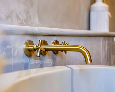 Robinet artisanal en cuivre doré pour salle de bain avec vasque blanc.