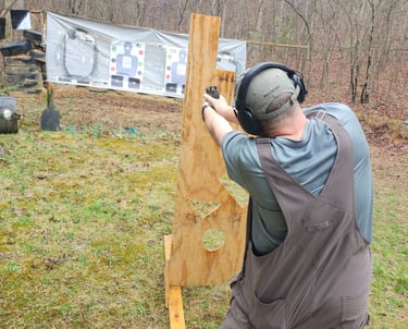 Man engaging targets from a barrier using self-defense firearm during training.