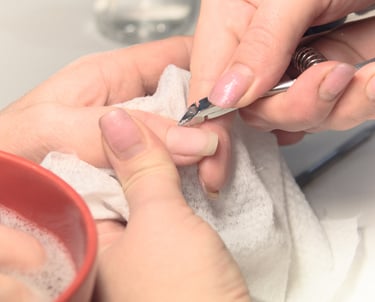 Someone is performing a manicure and using a cuticle trimmer for precision