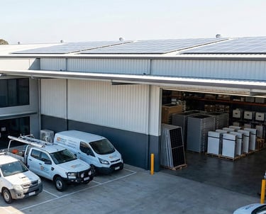 Warehouse with rooftop solar panels, open loading bay, and service vans parked outside.