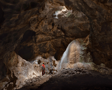 Persona explorando el interior de la Cueva la Tinaja, en un ambiente oscuro y misterioso