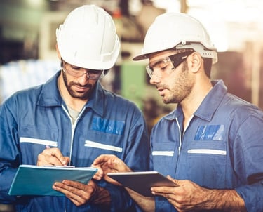 two men in blue workwears standing in a factory