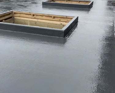 A waterproof grey GRP fiberglass flat roof installation with two rectangular skylight frames.