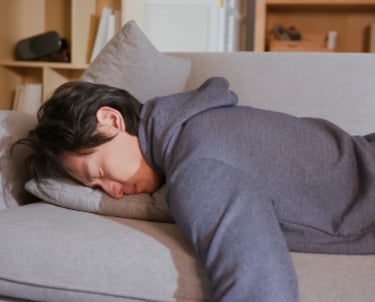 a man is resting on a couch with face in a pillow