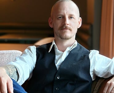 a man sitting on a couch with his arm resting on a chair