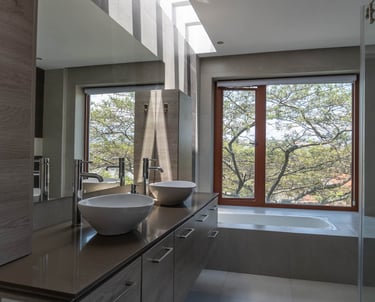 fotografía inmobiliaria quito ecuador tumbaco baño elegante y sobrio con dos lavabos y vista a un árbol