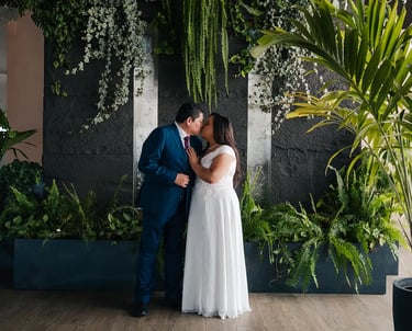 Retrato elegante de novios recién casados dándose un beso en entorno estético de plantas en Quito