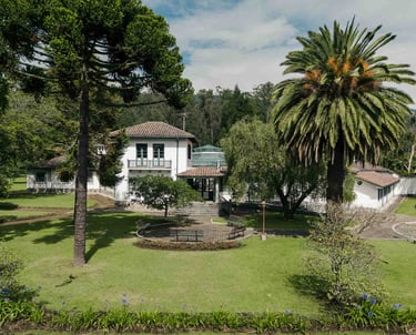 Fotografía con dron de mansión colonial de paredes blancas con techo naranja, cúpulas rodeada de naturaleza Quito Ecuador