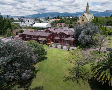 Fotografía aérea de gran casa religiosa de color rojo rodeada de hermoso jardín verde en Quito Ecuador
