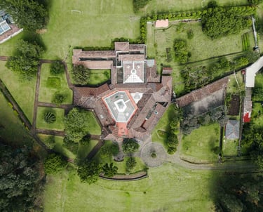 Fotografía con dron de mansión colonial de paredes blancas con techo naranja, cúpulas rodeada de naturaleza Quito Ecuador