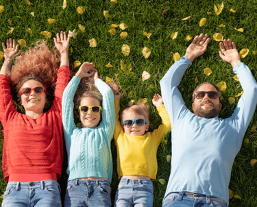une famille heureuse, deux parents et deux enfants allongés dans l'herbe avec des lunettes de soleil